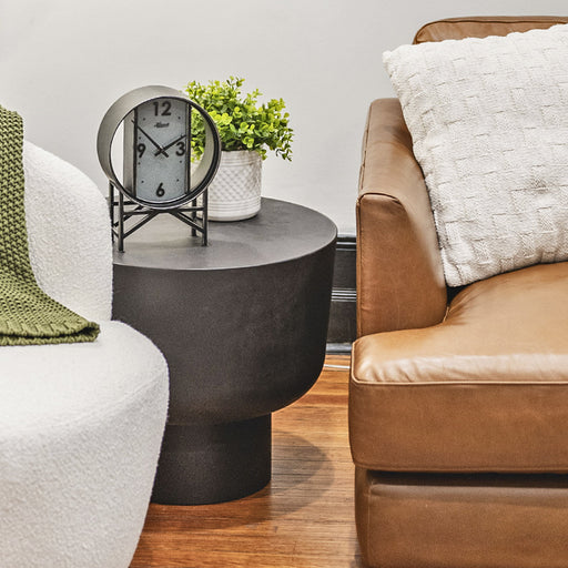 Living room with a black side table, clock, and potted plant between two couches.