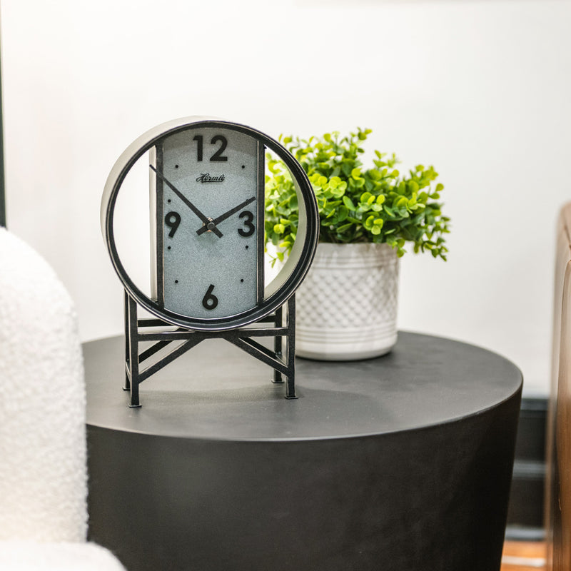 Vintage style clock on side table with green plant in white living room.