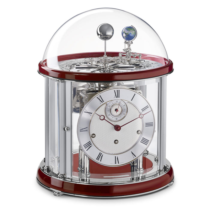 Red and silver Tellurium clock with glass dome and nickel plated mechanical gears visible on white background.