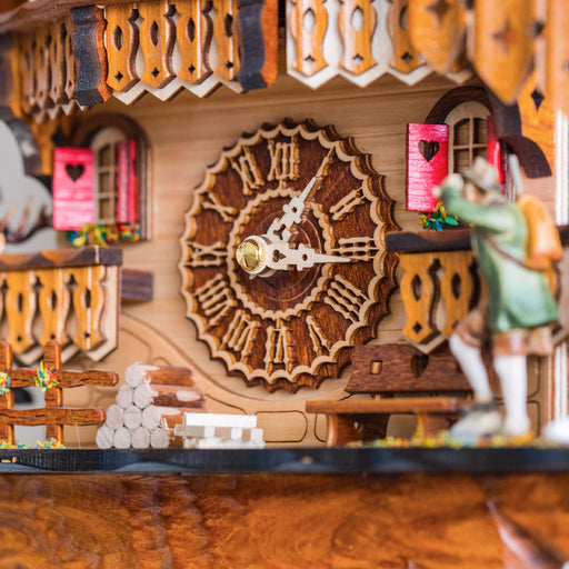Close up of decorative cuckoo clock face with wooden carved numbers and red shutters 