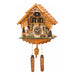 Intricate wooden cuckoo clock with figurines of deer and people next to trees
