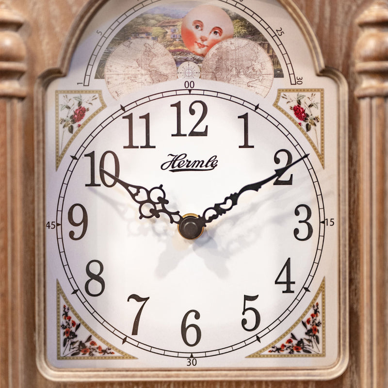 Close up of illustrated clock face with moon dial on wooden clock. 