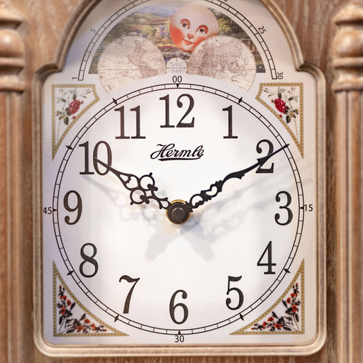 Close up of illustrated clock face with moon dial on wooden clock. 