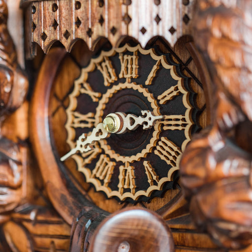 Close-up of a wooden cuckoo clock with intricate carvings and a detailed face.