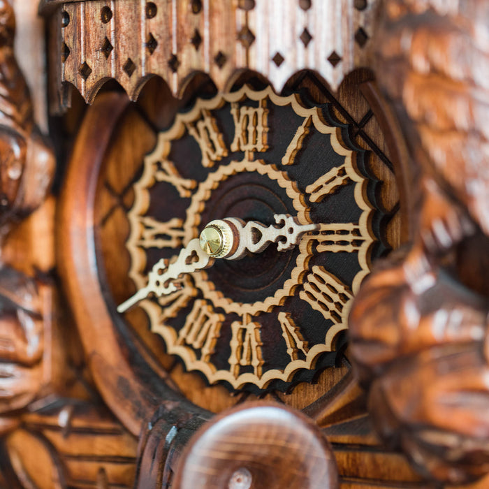 Close-up of a wooden cuckoo clock with intricate carvings and a detailed face.