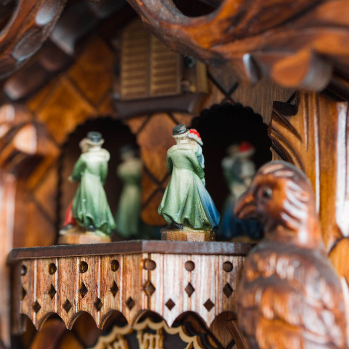 Close-up of dancing figures on top of wooden cuckoo clock 