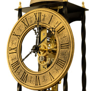 Close up of antique-style brass clock face and gears on white background.