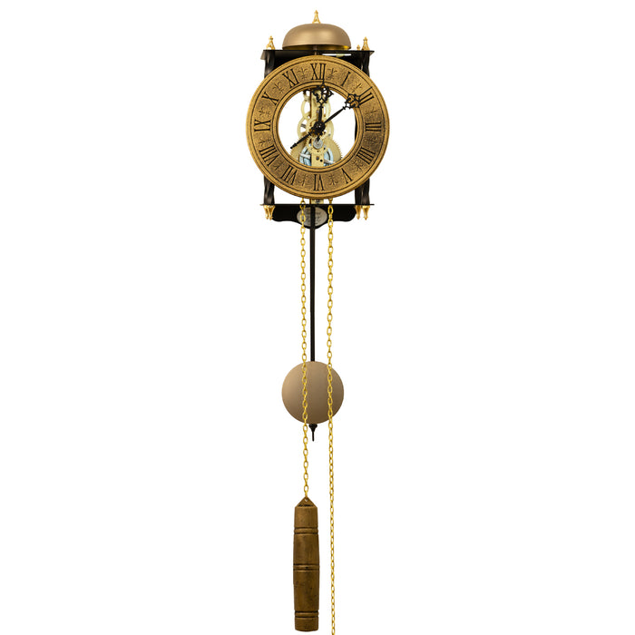 Skeleton clock with antique-style brass face and etched roman numerals on white background with brass chains and single weight hanging down.