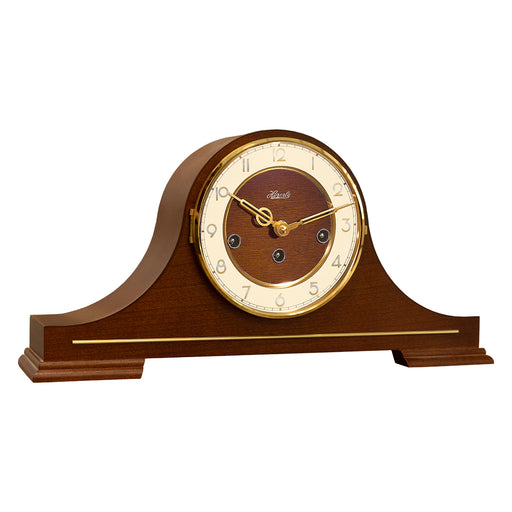 Wood and brass mantel clock with Hermle logo and three winding holes on white background.