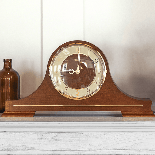 Wooden mantel clock on a white surface with a white wall background