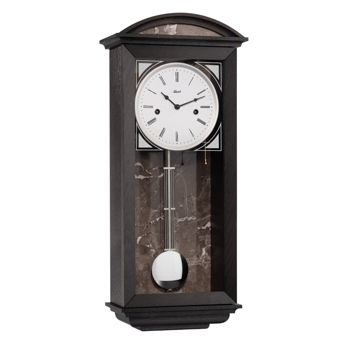 Black wood wall clock with nickel pendulum and two holes in the face for winding the mechanical movement inside.
