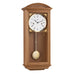 Natural oak wood wall clock with brass pendulum and two holes in the face for winding the mechanical movement inside.