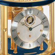 Up close of Tellurium clock face with silver color and roman numerals behind brass framed glass.