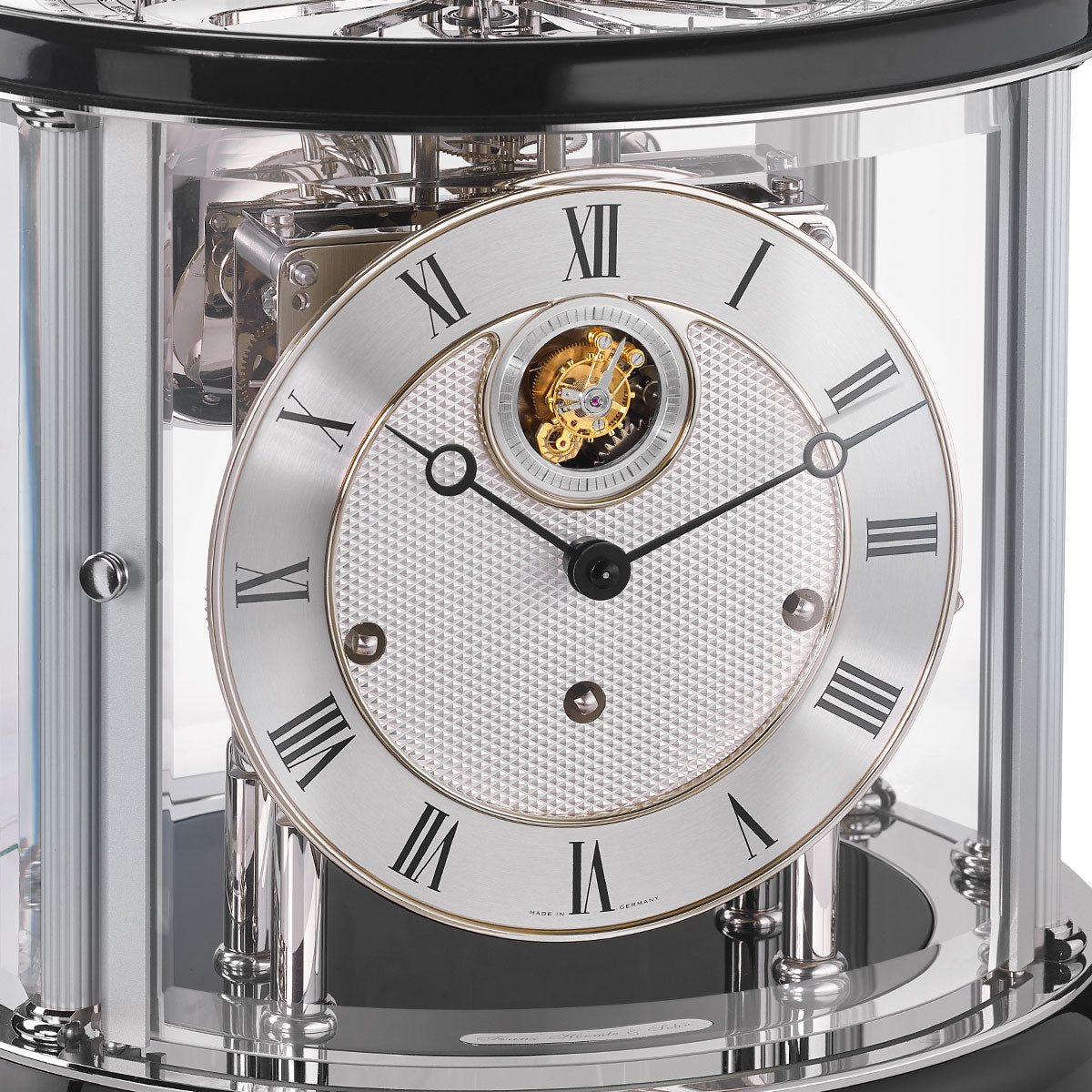 Up close of Tellurium clock face with silver color and roman numerals behind nickel framed glass.