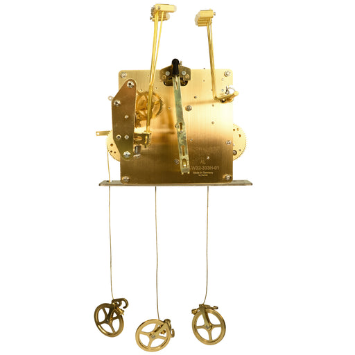 Back of a brass clock movement with number markings and hammers on white background.