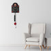 Black and red decorative wall clock hanging in white living room above white chair.