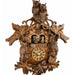 Close-up of ornate wooden cuckoo clock with owls and dancing figurines.