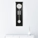 Black regulator wall clock hanging on white wall above white dresser