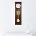Walnut wood regulator wall clock hanging on white wall above white dresser